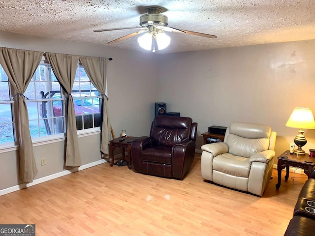 living area featuring ceiling fan, a textured ceiling, and light hardwood / wood-style flooring