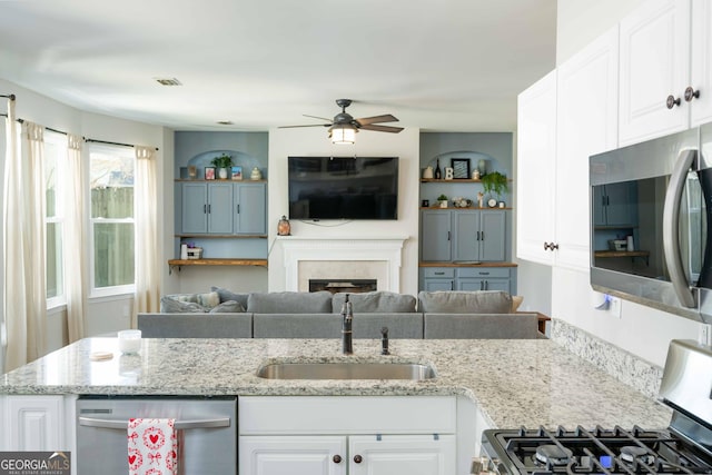 kitchen featuring sink, white cabinets, ceiling fan, stainless steel appliances, and light stone countertops