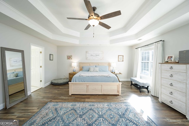 bedroom with dark wood-type flooring, ceiling fan, ornamental molding, and a tray ceiling