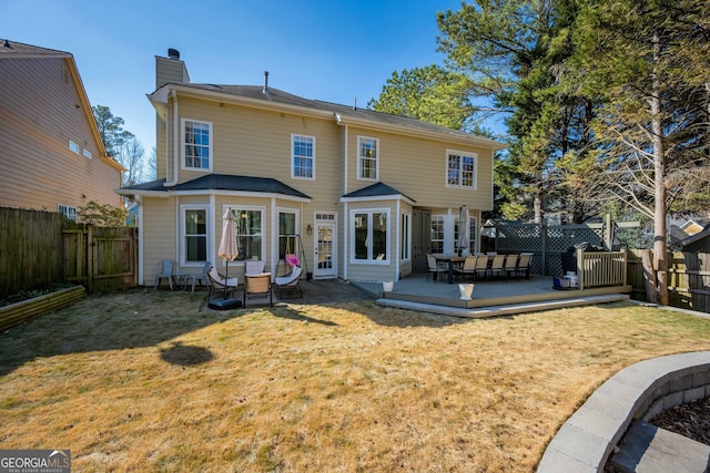 back of property with a wooden deck and a yard