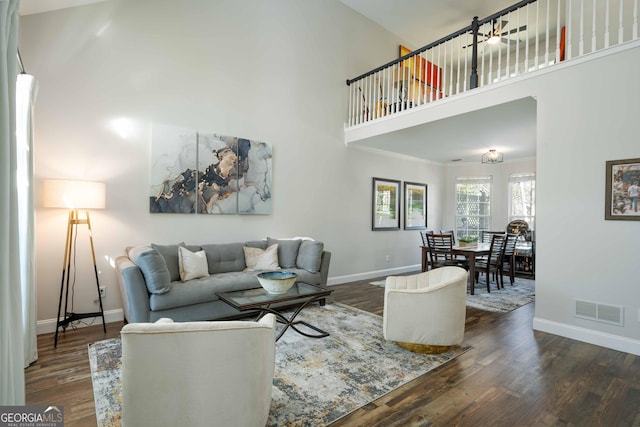 living room with ornamental molding, a towering ceiling, and dark hardwood / wood-style flooring