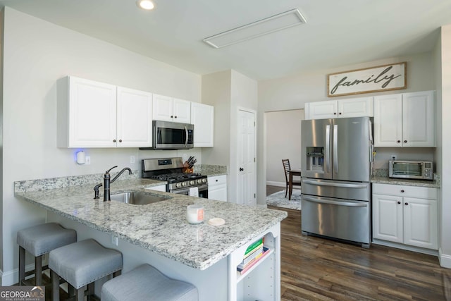 kitchen with sink, white cabinets, light stone counters, kitchen peninsula, and stainless steel appliances