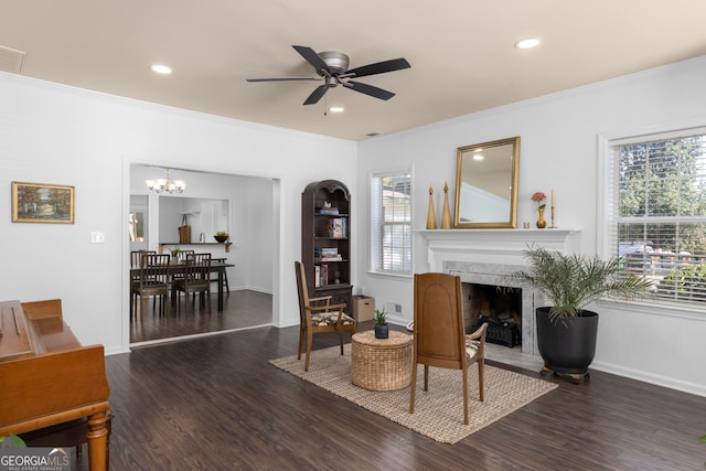 sitting room featuring ornamental molding, dark wood-type flooring, ceiling fan with notable chandelier, and a high end fireplace