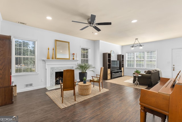 living room with ceiling fan with notable chandelier, a high end fireplace, dark hardwood / wood-style floors, and a healthy amount of sunlight