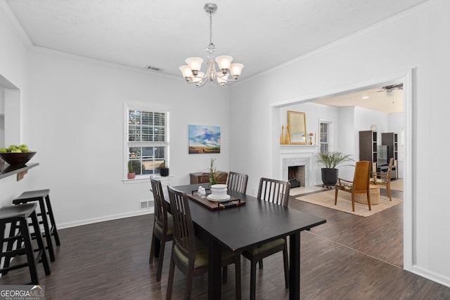 dining space with crown molding, dark wood-type flooring, and ceiling fan with notable chandelier