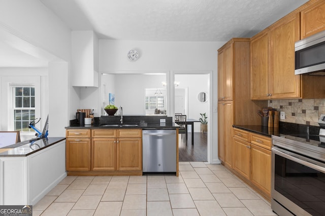 kitchen featuring sink, decorative backsplash, kitchen peninsula, and appliances with stainless steel finishes