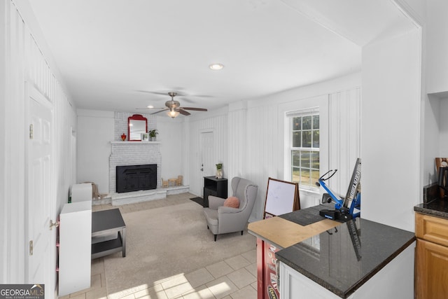 tiled living room featuring ceiling fan and a fireplace