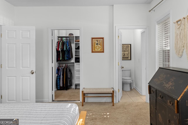 bedroom featuring ensuite bath, a spacious closet, light colored carpet, and a closet