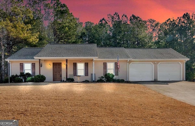 single story home featuring a garage and a lawn