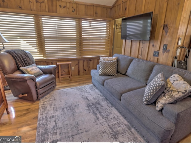 living area featuring wooden walls, vaulted ceiling, and wood finished floors