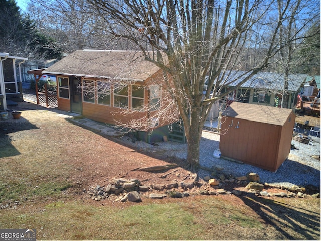 view of yard featuring a storage shed, an outdoor structure, and a sunroom