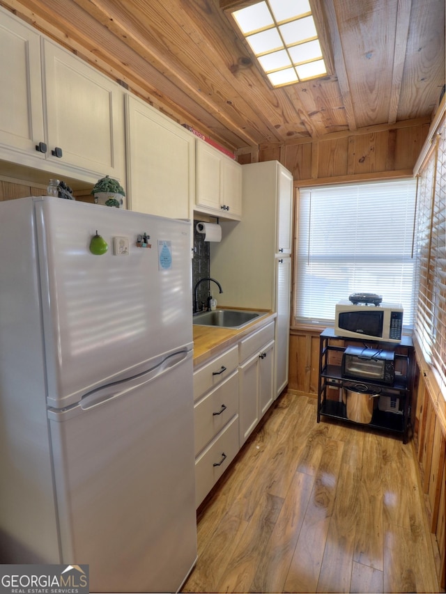 kitchen featuring white appliances, wooden ceiling, a sink, and white cabinets