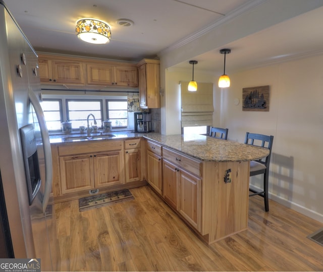 kitchen featuring a kitchen breakfast bar, crown molding, light wood-style floors, stainless steel refrigerator with ice dispenser, and a sink