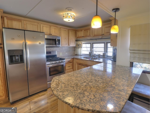 kitchen featuring crown molding, tasteful backsplash, appliances with stainless steel finishes, a sink, and a peninsula