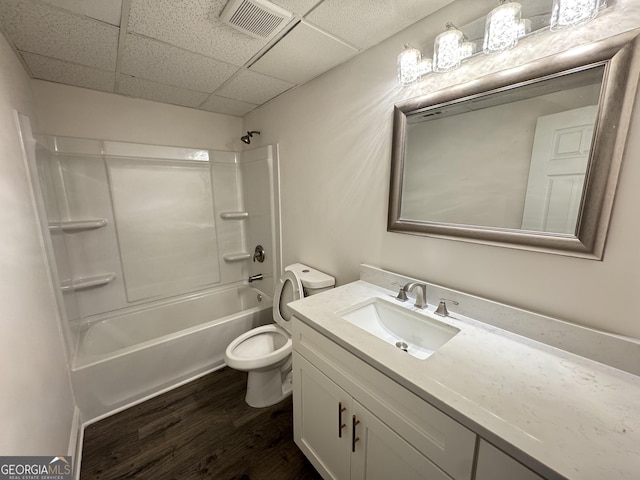 full bathroom featuring shower / bathing tub combination, vanity, wood-type flooring, a drop ceiling, and toilet