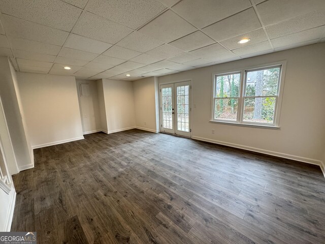 unfurnished room featuring a drop ceiling, dark wood-type flooring, and french doors