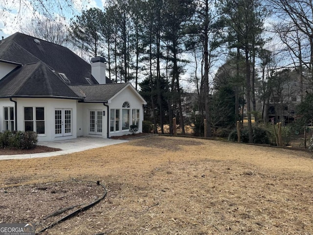 rear view of house featuring french doors, a patio, and a lawn