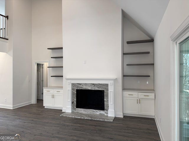 unfurnished living room with dark hardwood / wood-style flooring, high vaulted ceiling, and a high end fireplace