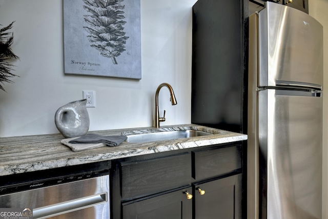 kitchen with light stone countertops, appliances with stainless steel finishes, and a sink