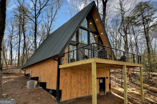 view of property exterior with a wooden deck, central AC unit, and metal roof