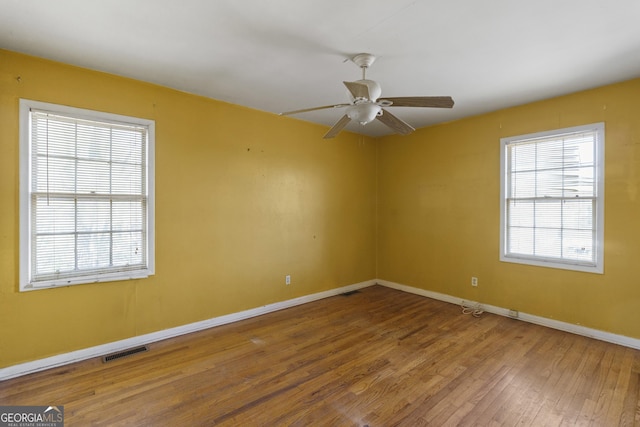 spare room featuring plenty of natural light, hardwood / wood-style floors, and ceiling fan