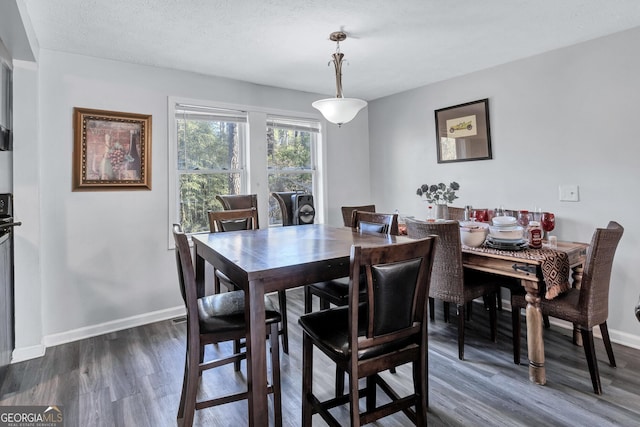 dining space with dark hardwood / wood-style floors and a textured ceiling