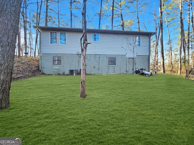 rear view of property featuring central AC unit and a lawn