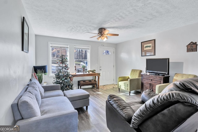 living room featuring a textured ceiling, light hardwood / wood-style flooring, and ceiling fan