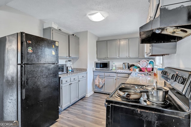 kitchen with sink, light hardwood / wood-style flooring, gray cabinets, appliances with stainless steel finishes, and a textured ceiling