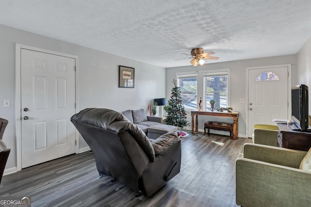 living room with ceiling fan, dark hardwood / wood-style flooring, and a textured ceiling