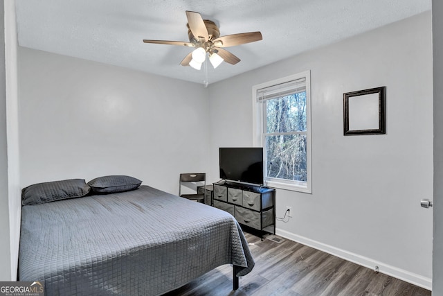 bedroom featuring ceiling fan, wood-type flooring, and a textured ceiling