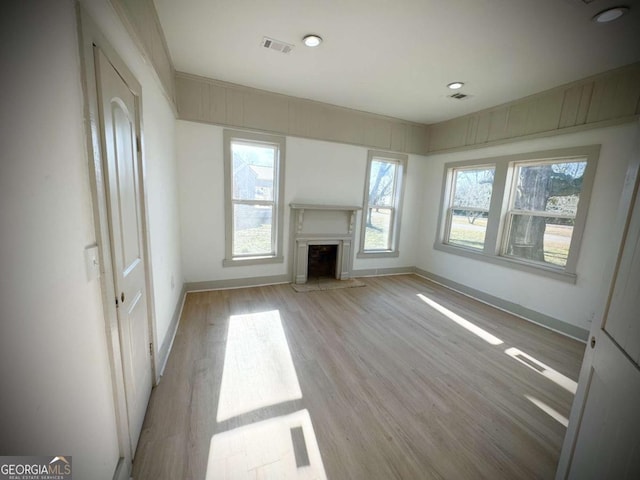 unfurnished living room featuring plenty of natural light and light wood-type flooring