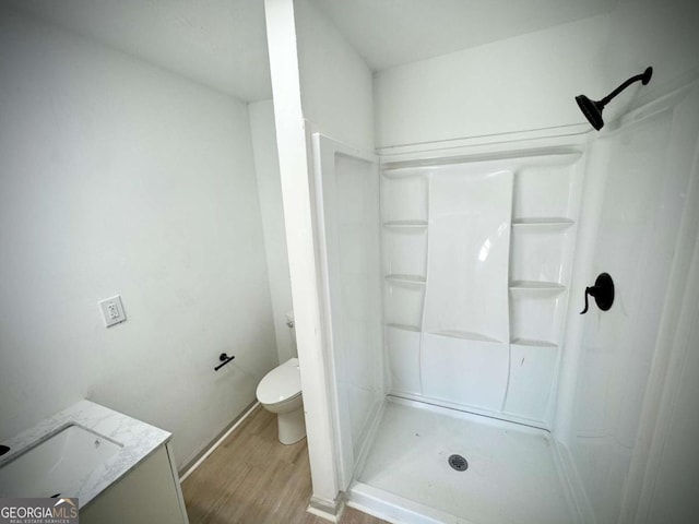 bathroom featuring a shower, hardwood / wood-style floors, vanity, and toilet