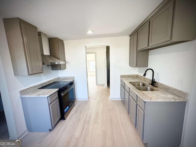 kitchen with wall chimney exhaust hood, sink, electric range oven, light wood-type flooring, and gray cabinets