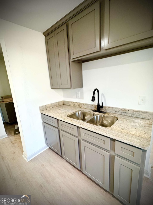 kitchen with light stone countertops, sink, and light wood-type flooring