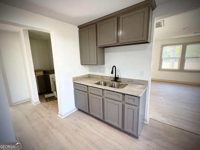 kitchen featuring sink, light stone counters, and light hardwood / wood-style flooring