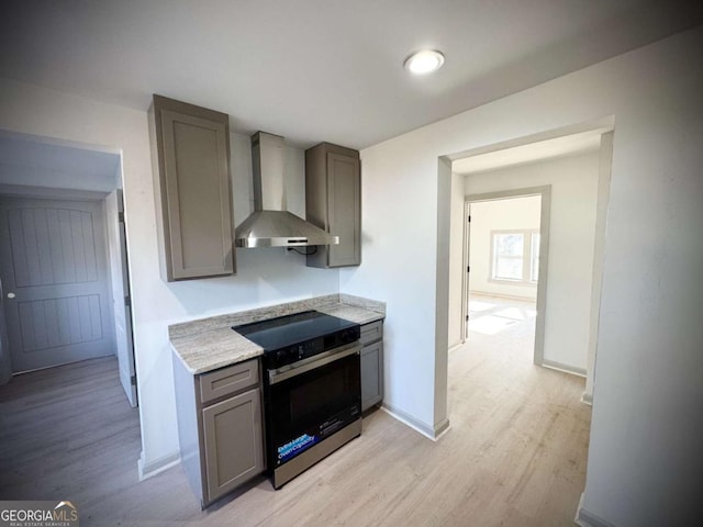 kitchen with electric range, gray cabinets, wall chimney exhaust hood, and light wood-type flooring