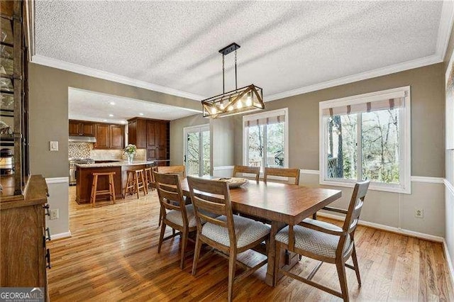 dining space featuring light wood-type flooring, baseboards, and ornamental molding