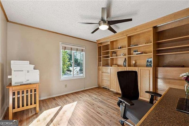 home office with baseboards, ceiling fan, crown molding, a textured ceiling, and light wood-style floors