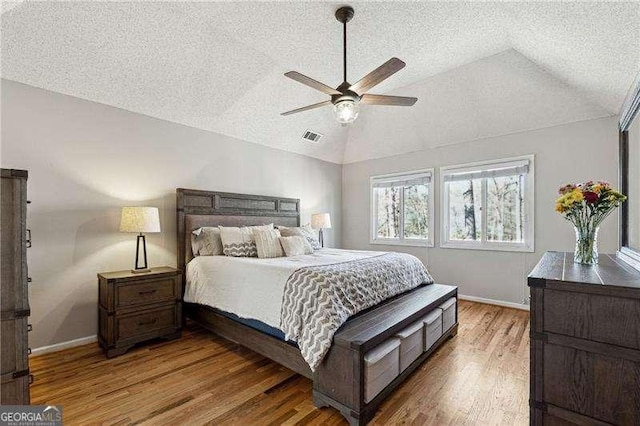 bedroom featuring baseboards, visible vents, vaulted ceiling, and wood finished floors