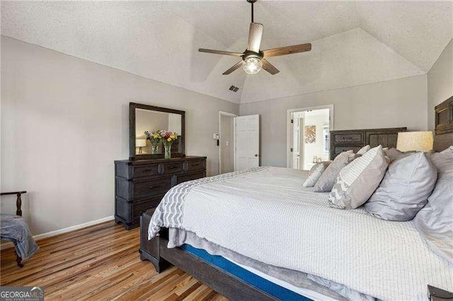 bedroom with vaulted ceiling, light wood finished floors, a textured ceiling, and baseboards