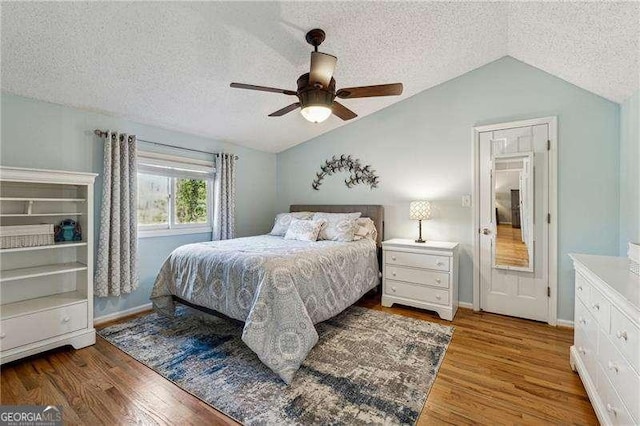 bedroom with lofted ceiling, ceiling fan, a textured ceiling, and wood finished floors