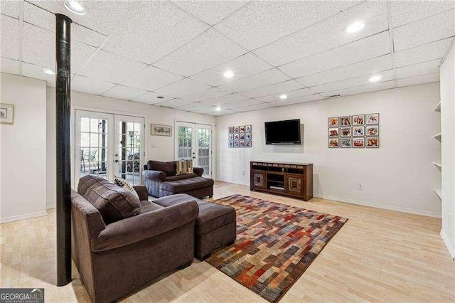 living area with a paneled ceiling, baseboards, wood finished floors, and french doors