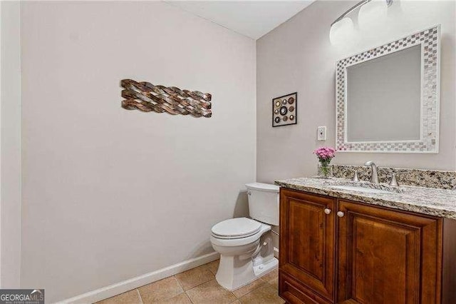 half bathroom featuring toilet, vanity, baseboards, and tile patterned floors