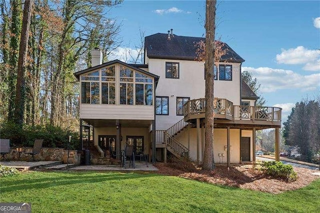 rear view of property with a sunroom, a chimney, stairway, a wooden deck, and a patio area