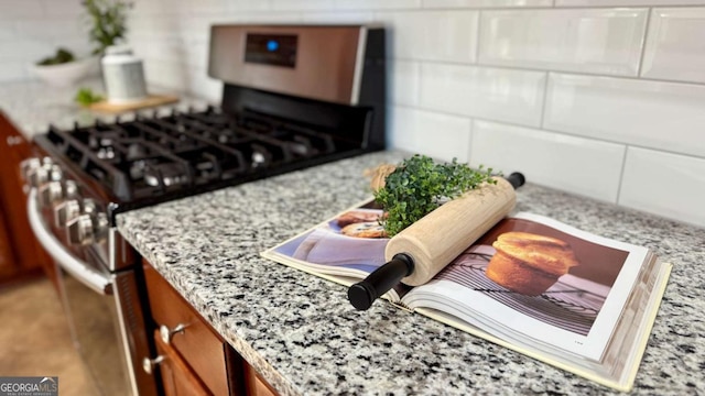 details featuring light stone counters and stainless steel range with gas stovetop