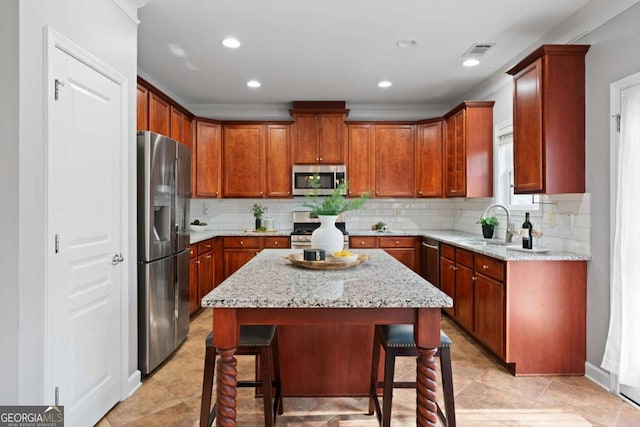 kitchen with sink, a kitchen breakfast bar, stainless steel appliances, a center island, and light stone countertops