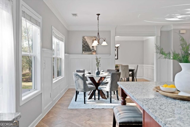 tiled dining room featuring an inviting chandelier and ornamental molding