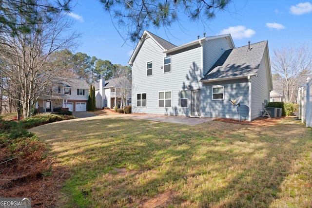 back of property with a garage, a lawn, and a patio