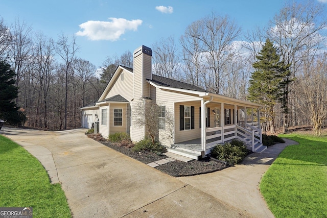 view of side of property featuring a porch, a yard, and a garage